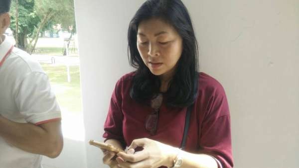 华妇陈明珠在投票站外按手机向有人投诉不满失去投票权。