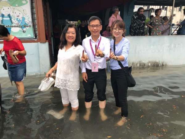 廖泰义(中）与家人脱鞋，涉入进入投票室投票。