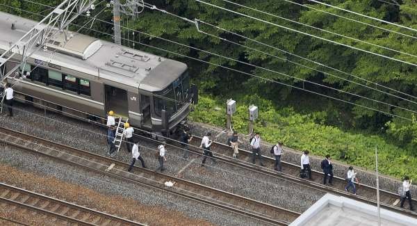 地震导致列车停驶，乘客下车沿着铁轨疏散。（美联社）