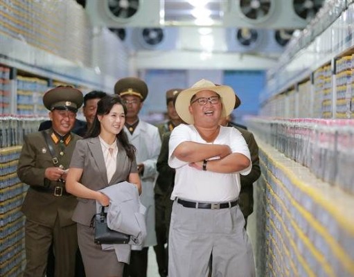 朝鲜最高领导人金正恩（图中央）与夫人李雪主（图左）一同巡视地方工厂。（网络图）