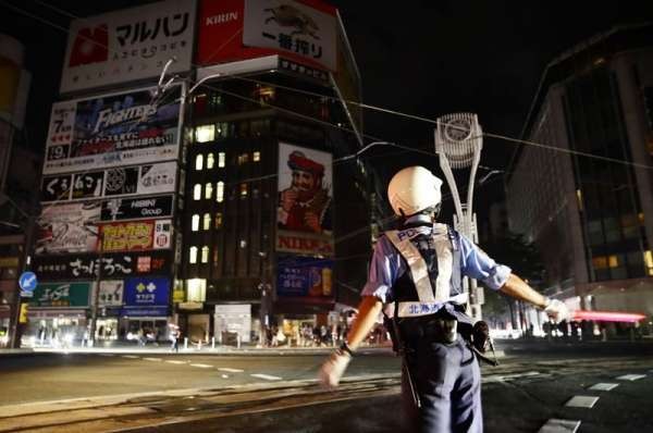 日本北海道发生规模6.7地震，境内有295万户停电，交警紧急指挥交通。（共同社）
