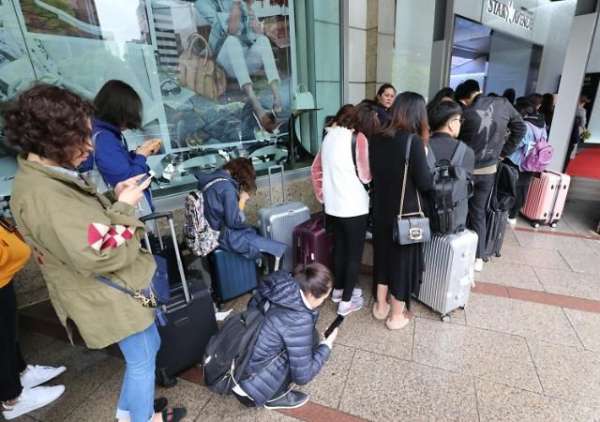 随着许多中国游客今年重新赴韩国游览，韩国零售商正积极联手中国流动支付平台。图为中国游客4月在首尔一免税店门前排队。 