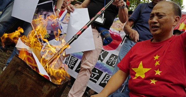香港亲中示威者焚烧横幅“反对美国发动贸易战”。