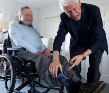 克林顿亲自为老布什穿上印有自己肖像的袜子。