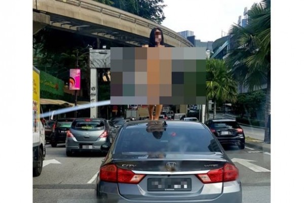 全裸的跨性人爬上一辆车的车顶。