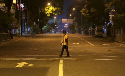 一名男子星期日晚行经空荡荡的科伦坡街头。（美联社）