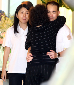 一名亲友拥抱李深静幼子兼IOI产业总执行长李耀昇（右）给予慰问，旁为李耀昇妻子即能源、工艺、科学、气候变化及环境部长杨美盈。