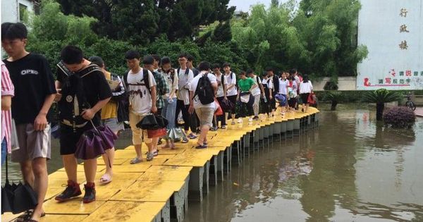 周五是中国2019年全国高考第一天，江西上饶市玉山县前天遭遇大暴雨，城区部分地区积水，当地一个考点的老师们用课桌临时拼成一座“浮桥”，让考生们顺利进入考场考试。（新华社） 