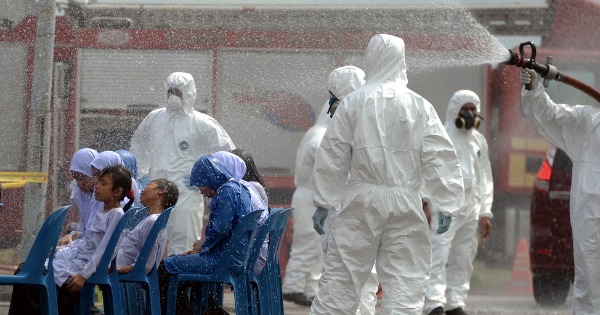 受空气污染影响的丹绒布蒂里度假村国小学生，被送到巴西古当室内体育馆行动中心；工作人员向学生洒水，以清洗他们身上可能出现的病菌。