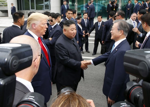 美国总统特朗普（左）与韩国总统文在寅（右）30日在分隔南北韩的非军事区与朝鲜领导人金正恩（中）会面。