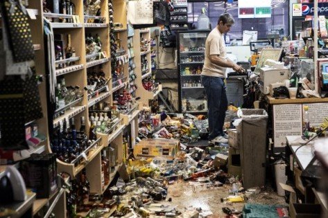 里奇雷斯特镇一间汽油站酒商店的雇员星期六清理满地都是地震时跌落的酒类和货品。（欧新社）