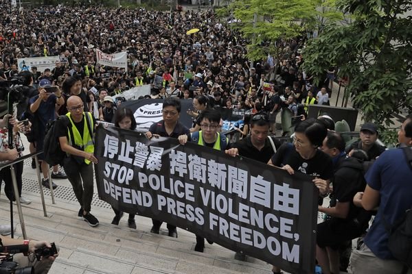 黑衣示威者星期日静默游行，抗议警方在“反送中”示威中针对记者的暴力行为。（美联社）