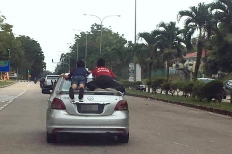 两名孩童趴在车后的挡风玻璃，如此行径，让人捏一把冷汗。