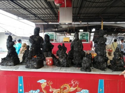 理事会成员将废墟中寻获的神像并列摆放在庙外长桌上，可见到全都  被烧毁焦黑一片。