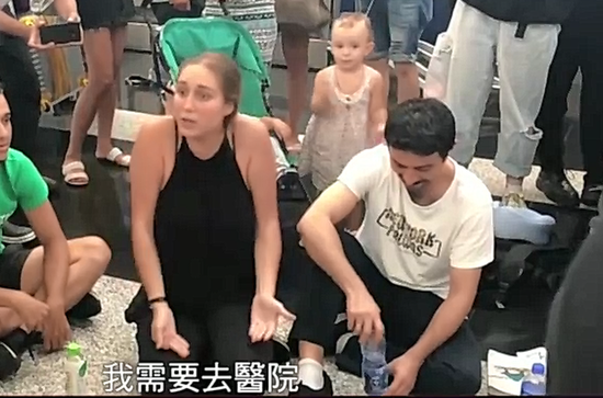 女游客情绪几近崩溃，下跪恳求示威者停止示威，让她能够回国治疗。 