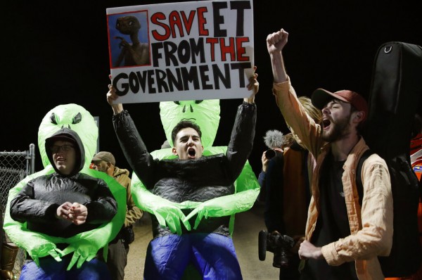 部分民众戴着锡纸帽及外星人面具，其他人士手持标语，上面写著“把外星人从政府处拯救出来！”