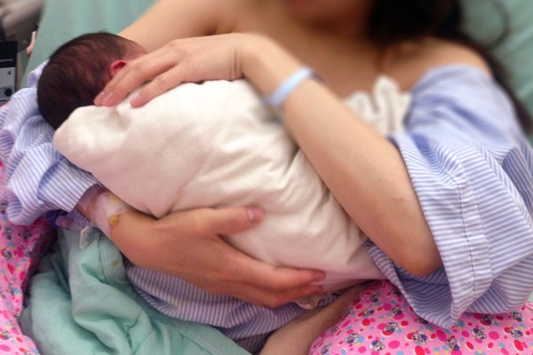 医院鼓励妈妈以坐着的姿势给宝宝喂奶。