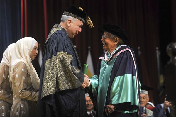 达因（右）周六在第58届马大毕业典礼上，从霹雳州苏丹纳兹灵莎殿下手中接领博士文凭。 