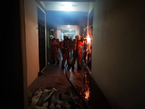 消拯员动用工具撬门，设法进入公寓内救火。