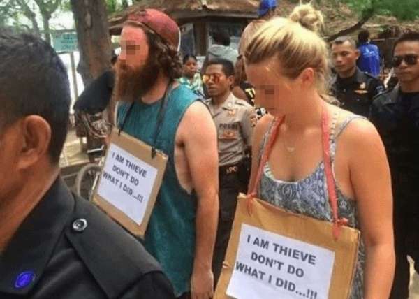 两人被迫带上写有“我是贼”的挂牌，在印尼街头示众。（互联网图片）