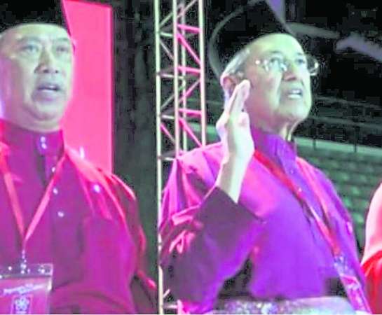 马哈迪（右）在土团党推介礼上与慕尤丁举起右手宣誓，以示团结一致。