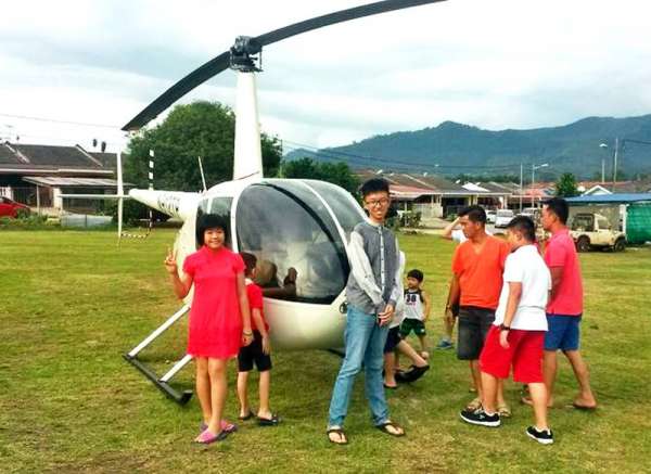 新加坡女婿自驾直升机回娘家拜年，直升机停放在花园区草场，引来村民的好奇围观。  