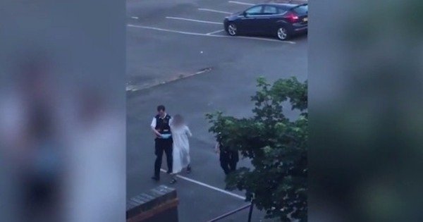 一名男子身穿白色长袍及拖鞋被警员押送。（互联网图片）