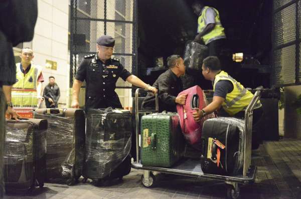 几名警员将一排行李箱搬上大卡车。