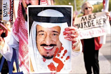 美国反战团体“粉红代码”（Code Pink）19日聚集白宫外，手持沙地阿拉伯国王萨勒曼的照片，针对沙地记者卡舒吉遭杀害一事示威。（彭博）