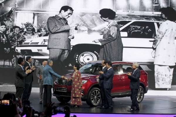 历史重演！马哈迪（左四）1985年推介首轮普腾赛佳，把车子钥匙递给妻子茜 蒂哈丝玛时的画面，现今出现在宝腾X70推介礼上。左三为雷京。 