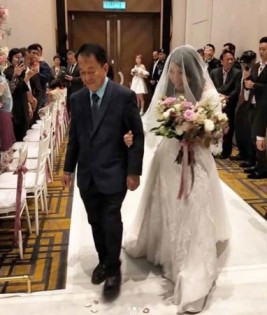 父亲杨福友（左）牵杨美盈进婚礼现场。（中国报图片）