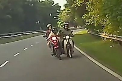 劫匪的摩托车从后方趋近受害者，然后伸手拿受害者放在摩托车篮的物品。 