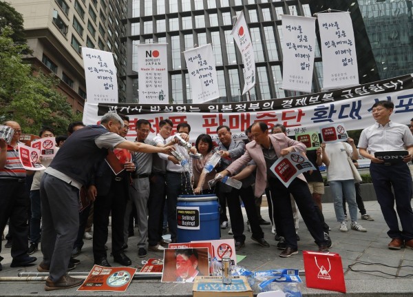 图为韩国中小企业主日前上街抗议日本出口限制，把日本啤酒喝运动饮料倒入垃圾桶。（美联社） 