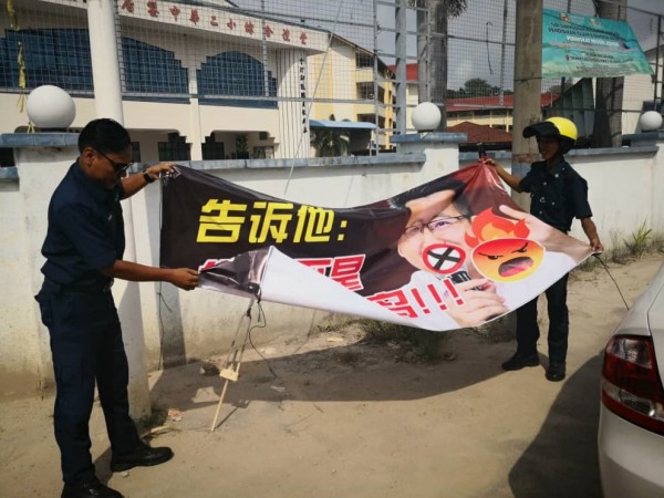 市议会执法人员接获民众投报后，将挂在中华二小礼堂前的横幅拆下。横幅上有刘镇东的肖像。