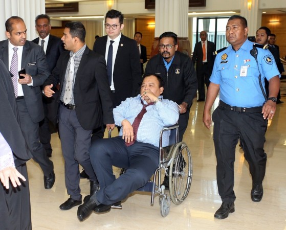 依丁沙兹里坐在轮椅上，由工作人员推离议会厅。