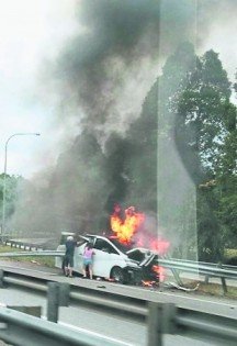 死者驾驶的轿车撞入分界堤着火，陈欣怡在好心人的帮助下，取出灭火器尝试扑灭火势。