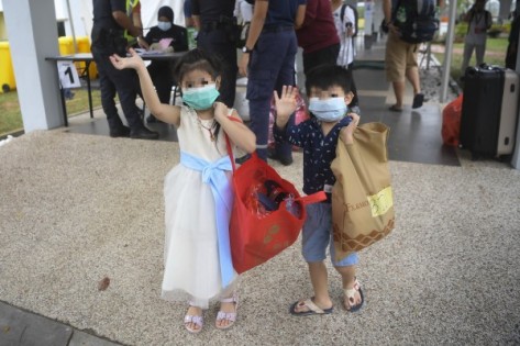 其中2名获准回家的儿童，开心向媒体挥手。