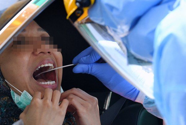 一名医护人员采集接受检验者的鼻腔及口咽样本。