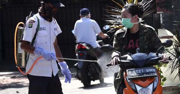 印尼南丹格朗卫生官员星期二对一名摩托骑士喷洒消毒剂预防冠病传播。（美联社）