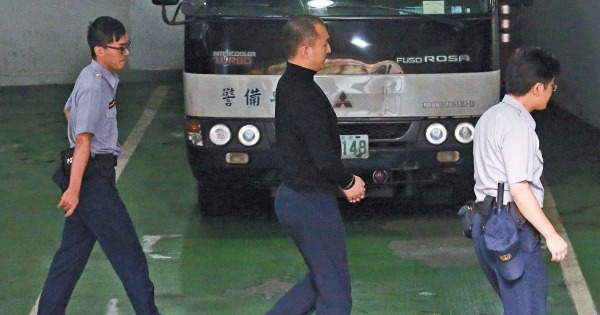中国居民周泓旭（中）昨天被台北地方法院宣判后，戴着手铐离开法院。（台湾联合报图）